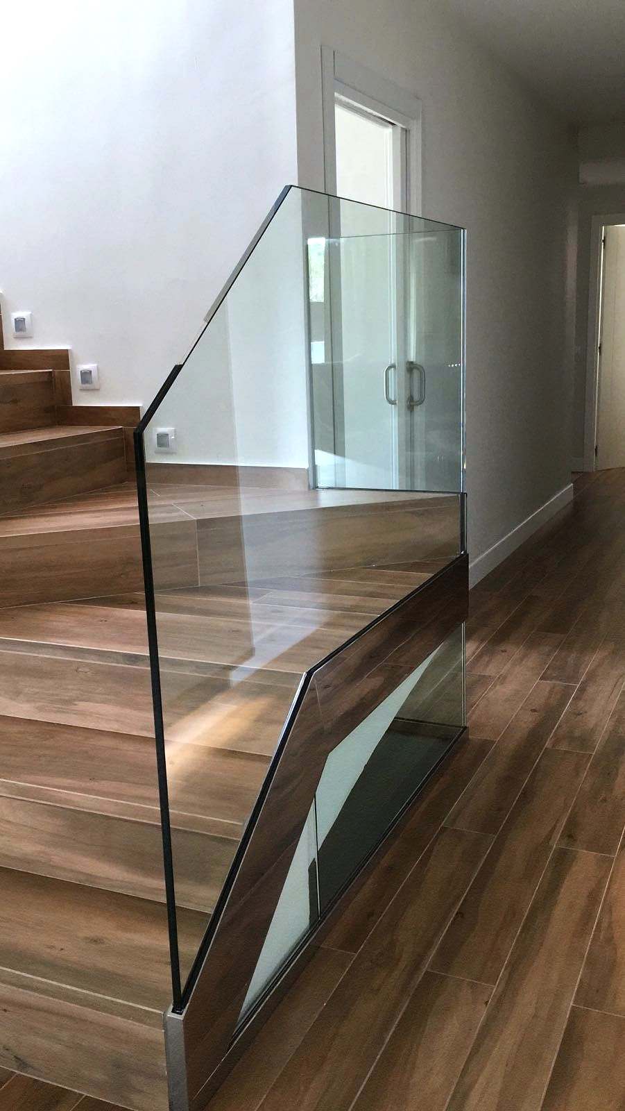 Escalera de madera con barandilla de vidrio que gira en el rellano