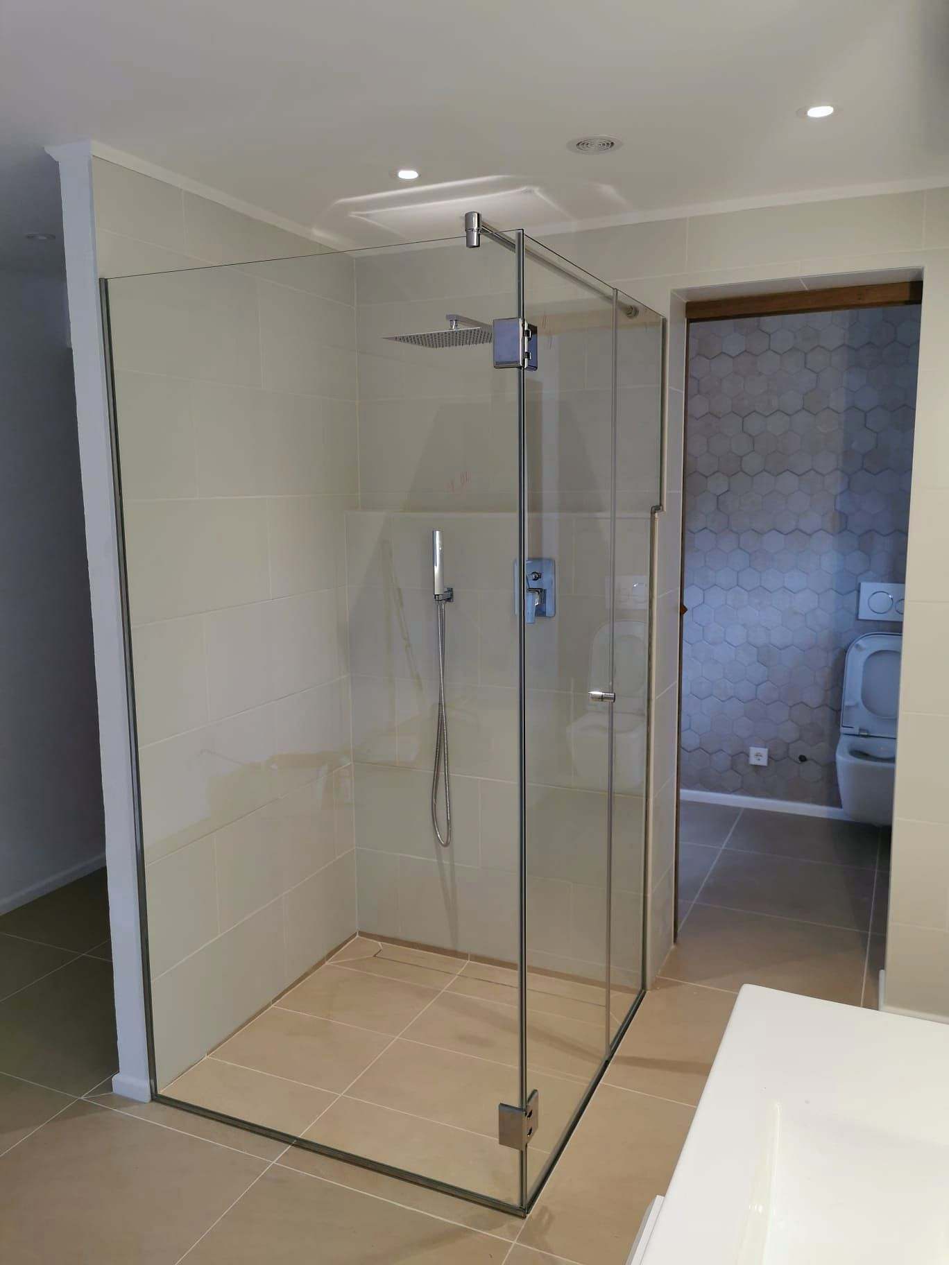 Ducha a ras de suelo cerrada con mampara angular de vidrio transparente y herrajes cromados