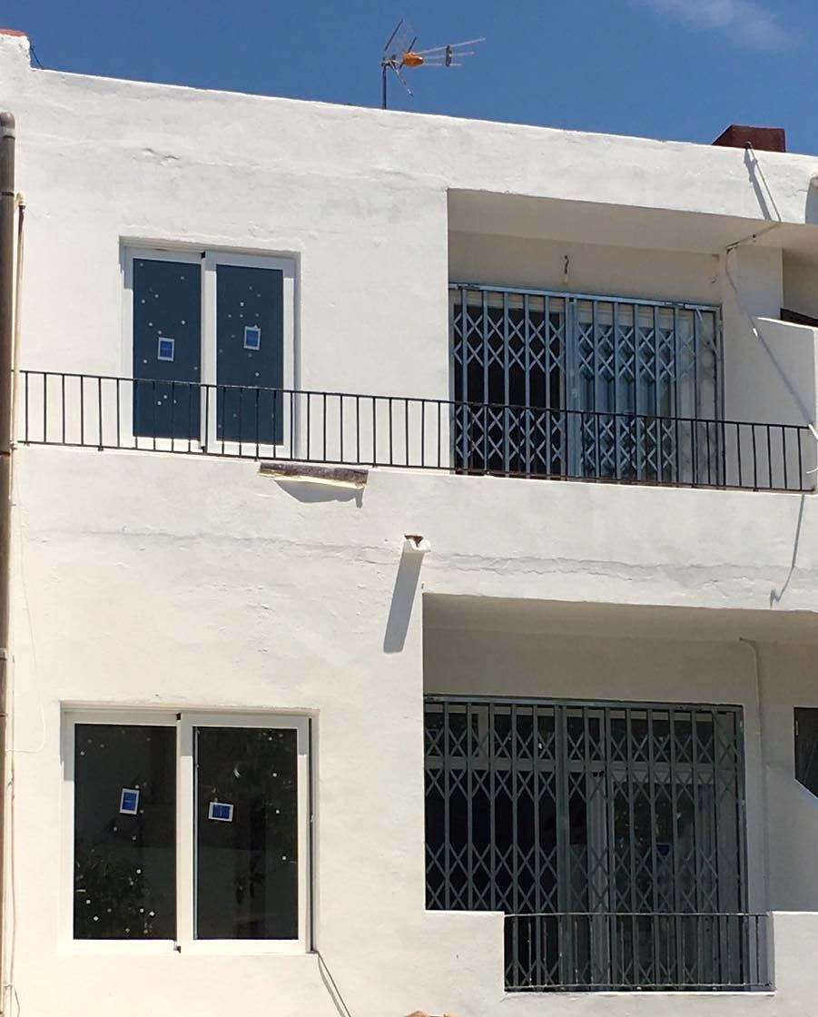 Fachada blanca de dos plantas con ventanas de aluminio nuevas